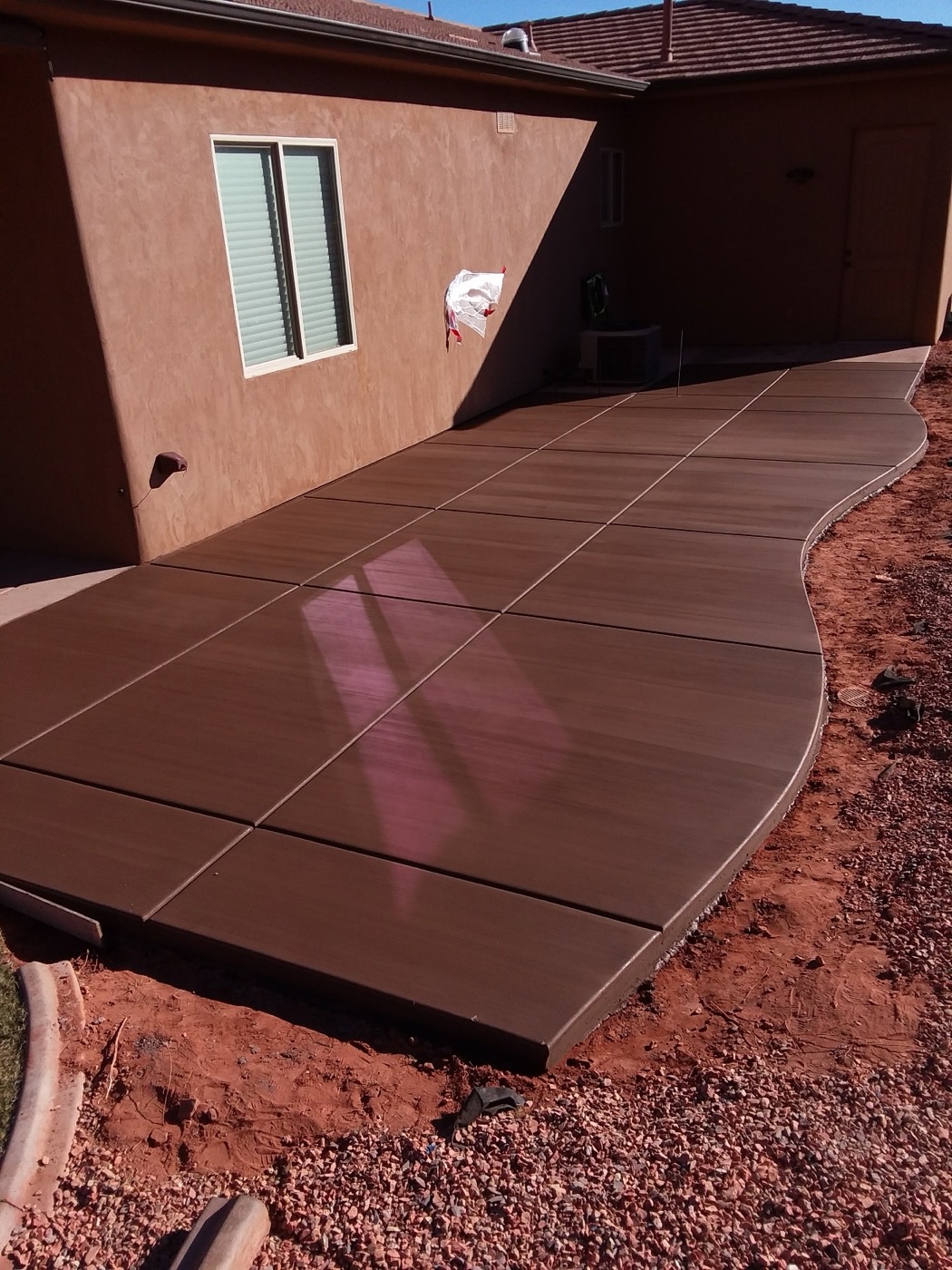A finished colored concrete walkway curving around a St. George home